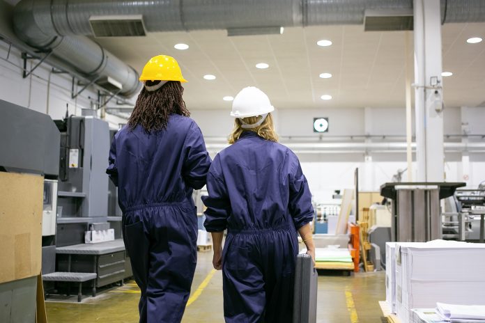 Diverse female factory workers in hardhats and overalls